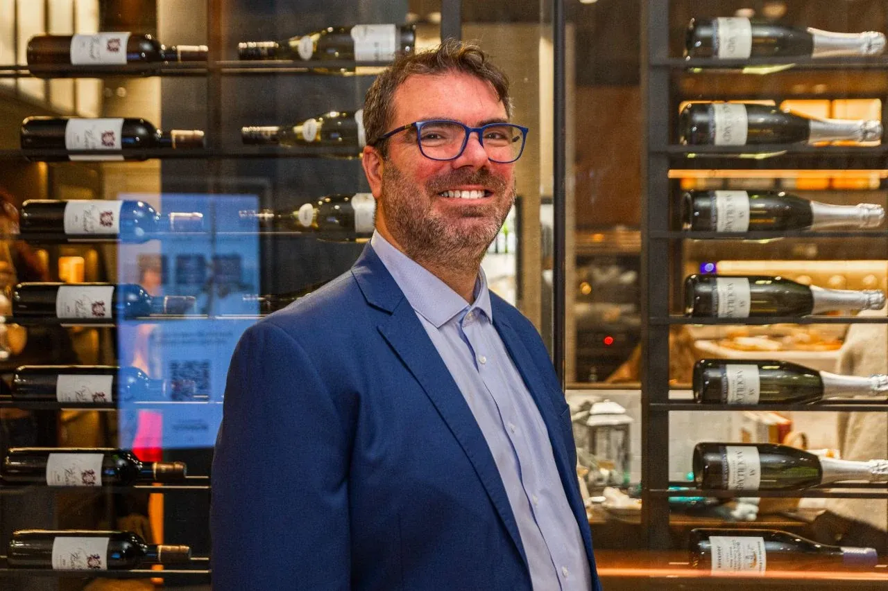 Alex Charasse in a blue suit, standing by a wine display.