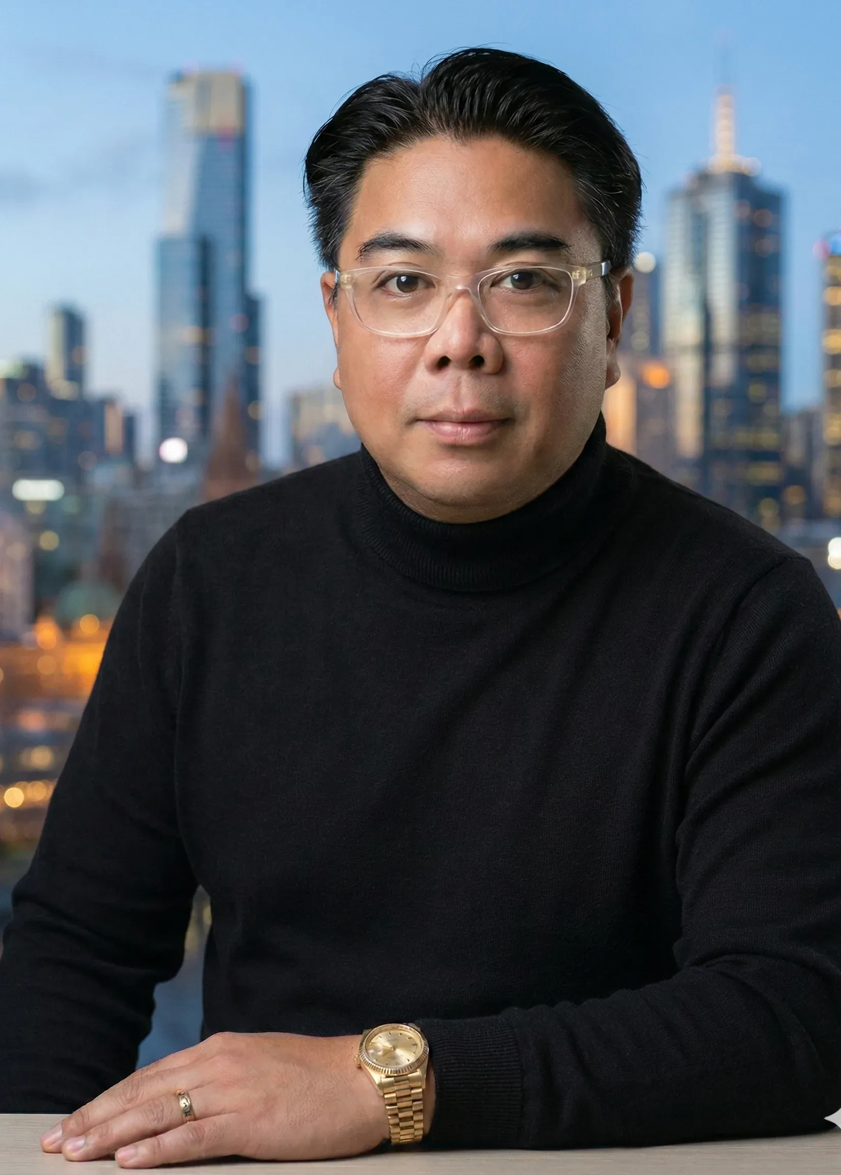 Rob Angeles in a black jumper, with the Melbourne skyline behind him.